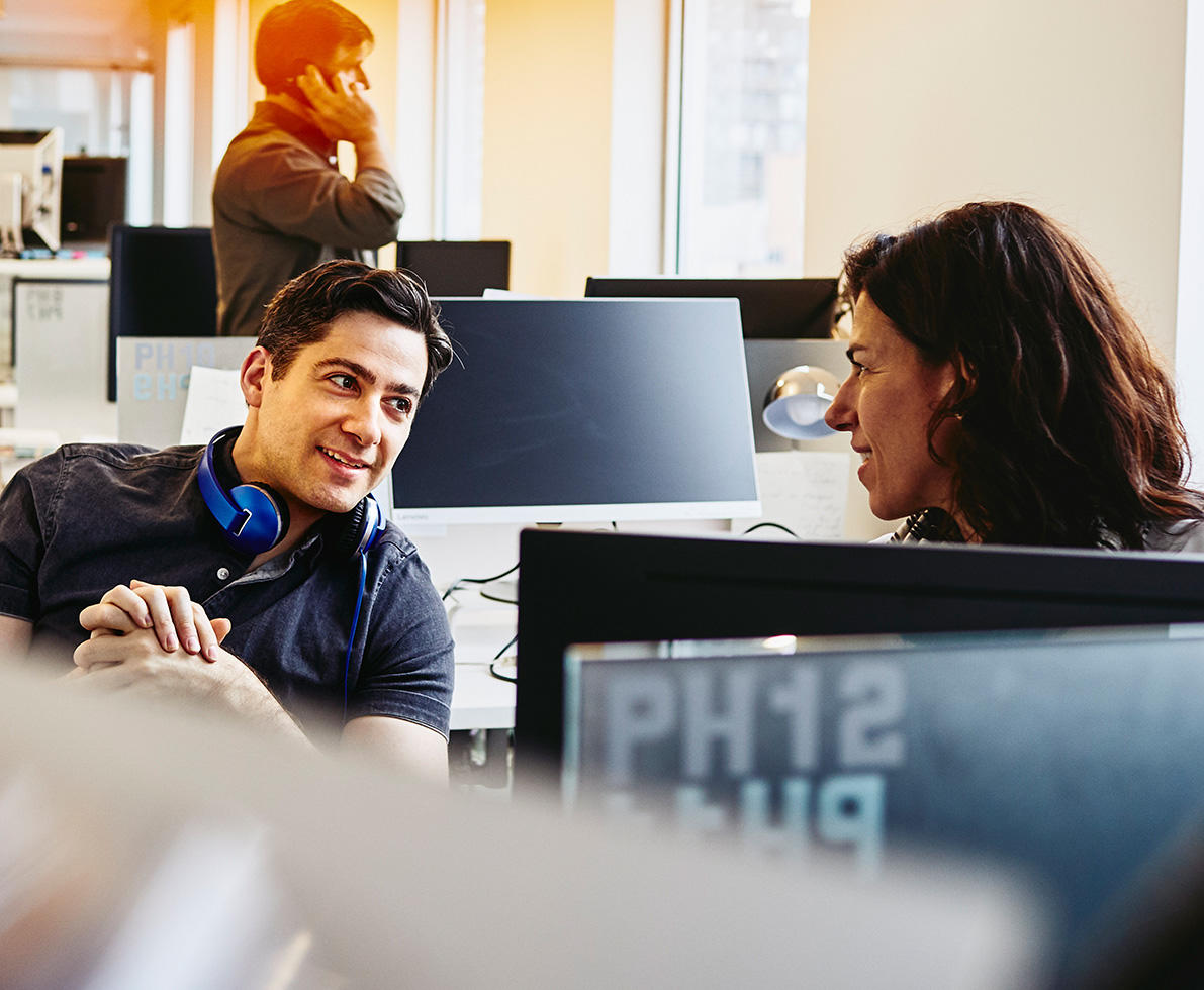 man and woman talking behind computer screen